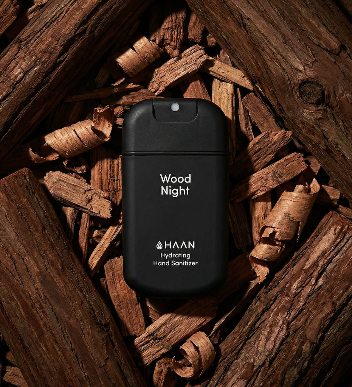 Black hand sanitizer bottle labeled 'Wood Night' by HAAN on a wooden background